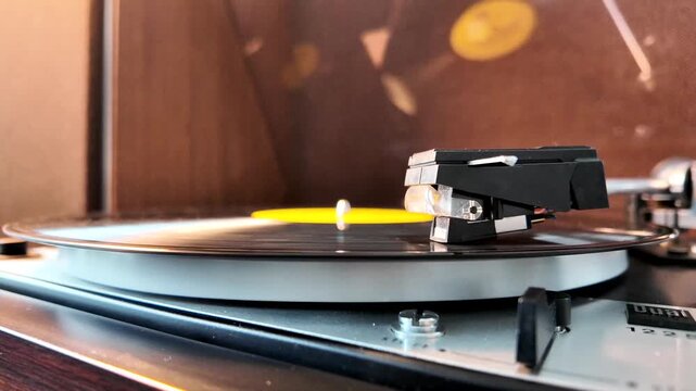 Vintage record player needle gently touching spinning vinyl disc close up in slow motion.