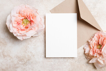 Blank white wedding card mockup on a beige background with envelope and rose flower. Elegant and minimalist flat lay for invitation or greeting card design © nikavera