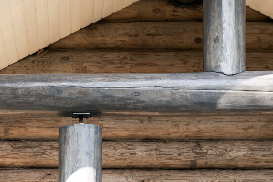 Rustic log cabin interior featuring exposed wooden beams and round timber support columns, emphasizing natural wood grain, weathered texture and traditional joinery for a cozy handcrafted architecture