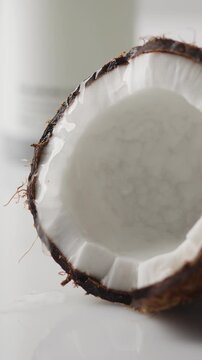 Coconut water pouring into a fresh half coconut fruit isolated on a white background with tropical ingredients for natural cosmetics