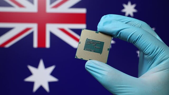 Close up view of hand in blue glove holding CPU microchip. Australian flag in blurred background. Concept of semiconductor shortage and artificial intelligence development in Australia.