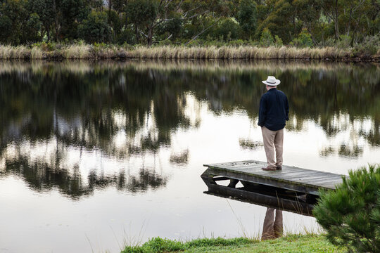 man wearing hat on wooden launch overlooking pond, Stanford, South Africa
