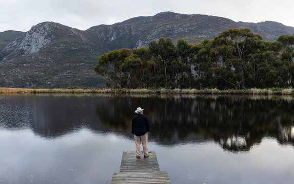 man wearing hat on wooden launch overlooking pond, Stanford, South Africa