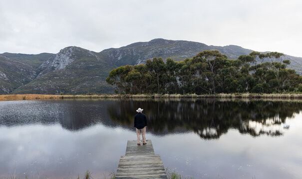 man wearing hat on wooden launch overlooking pond, Stanford, South Africa