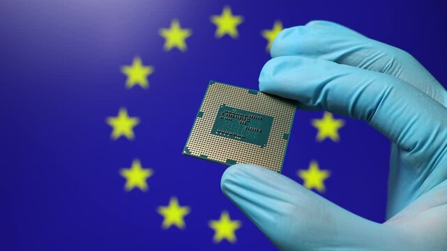 Close up view of hand in blue glove holding CPU microchip. European Union flag in blurred background. Concept of semiconductor shortage and artificial intelligence development in EU.