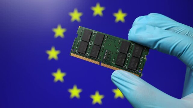 Close up view of hand in blue glove holding RAM memory microchip module. European Union flag in blurred background. Concept of semiconductor shortage, artificial intelligence development in EU.