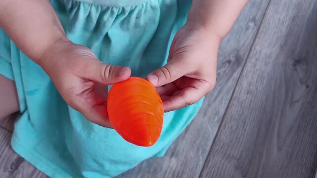 Child holds an orange toy carrot in both hands, colorful educational pretend play and imaginative childhood activity.