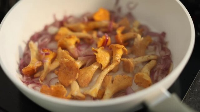 Chanterelle mushrooms and onions frying in a pan, capturing a rich and aromatic cooking process suitable for both home kitchen and professional restaurant preparation.
