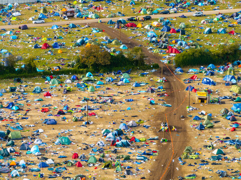 Reading, United Kingdom - 31 August 2026: Aerial view of the Reading Festival campsite filled with numerous colorful tents and people walking along dirt paths under a clear sky.
