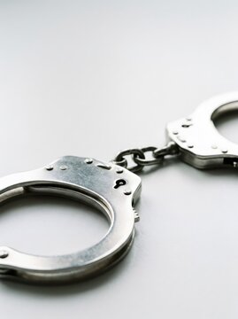 Steel handcuffs lying on white table in police station. Law enforcement and justice concept. Crime investigation, arrest and detention symbol for legal or security background.