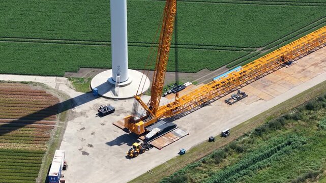 Heavy mobile crane assembling wind turbine tower in green field