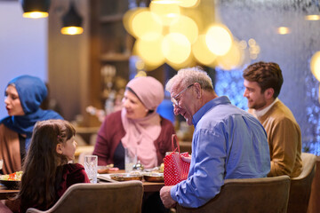 Fototapeta premium Multigenerational Family Gathering Around Dinner Table With Grandfather Giving Gift