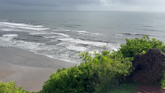 Scenic elevated view of ocean waves crashing on sandy beach from Chapora Fort hill in North Goa India