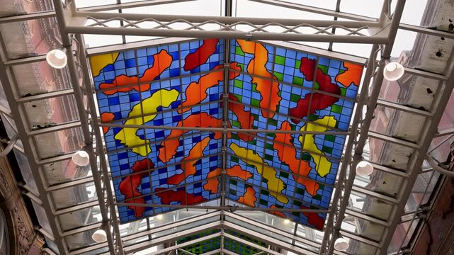Colorful stained glass roof by Brian Clarke fills the frame as the camera looks straight up along Queen Victoria Street in Victoria Quarter.