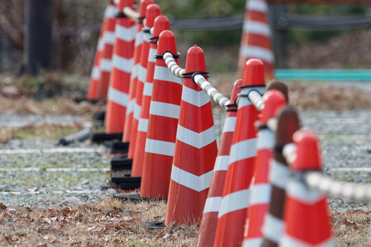 Row of red and white traffic cones linked with plastic barrier chain at construction site with copy space