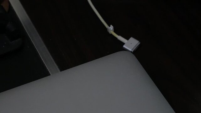 Close-Up of Hand Unplugging Power Charger Cable from Laptop