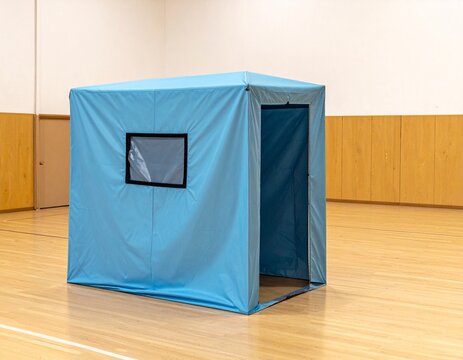 Blue privacy tent for an evacuation shelter standing on a wooden floor