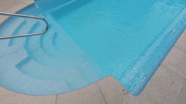 Clear Blue Swimming Pool Entry Steps with Metal Handrail at Resort