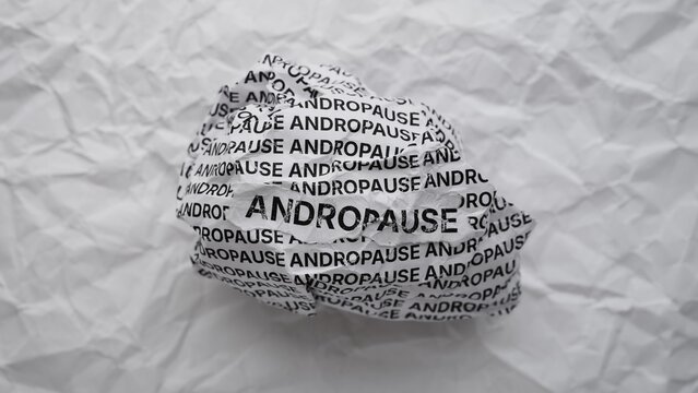 Close-up of a crumpled paper ball with words Andropause on a crumpled white paper background