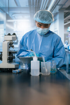 Medical or research scientist or doctor using looking at a test tube of clear solution in a lab or laboratory.