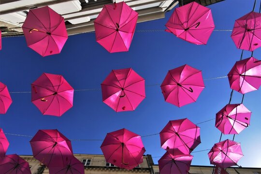 Vue de dessous de parapluies roses ouverts sous un fond de ciel bleu, symbolisant la lutte et la sensibilisation des femmes au d&eacute;pistage du cancer du sein