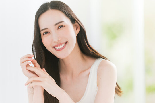 美しい肌と黒髪ロングヘアの笑顔の日本人女性。スキンケア・ヘアケアイメージ。