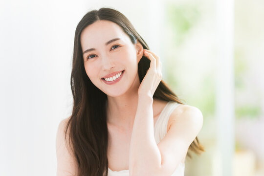 美しい肌と黒髪ロングヘアの笑顔の日本人女性。スキンケア・ヘアケアイメージ。