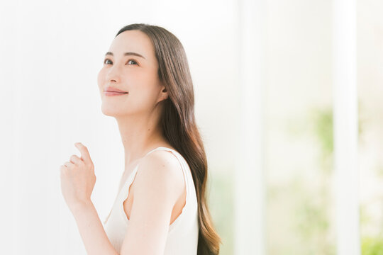 美しい肌と黒髪ロングヘアの笑顔の日本人女性。スキンケア・ヘアケアイメージ。
