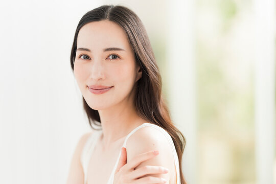 美しい肌と黒髪ロングヘアの笑顔の日本人女性。スキンケア・ヘアケアイメージ。