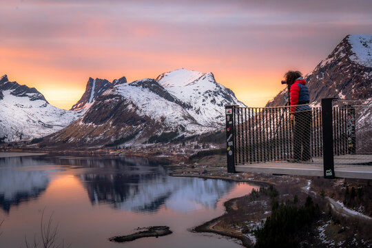 Photographer on a clifftop viewing platform above a fjord at sunset, Bergsbotn, Senja, Norway