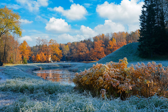 Sunlight hits the colorful oak grove and water while cold air creates a fresh morning scene in this peaceful European park landscape during October