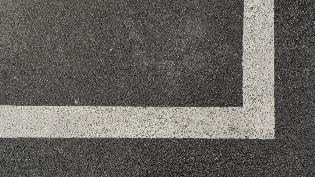 Dark asphalt road surface texture background with white painted line corner