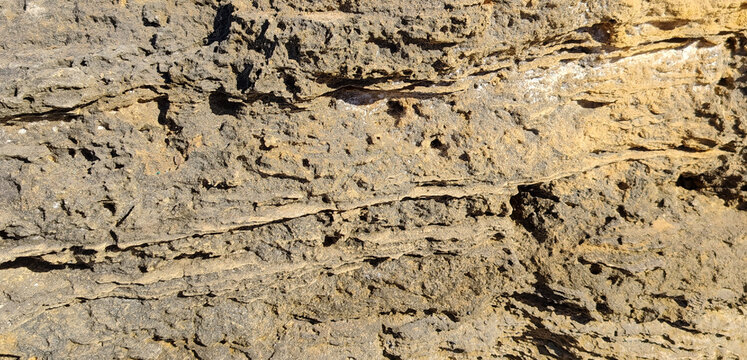 Eroded layered rock stone cliff surface texture background with natural fissures