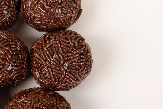 Traditional Brazilian chocolate brigadeiros coated in sprinkles, set against a white background with copy space.