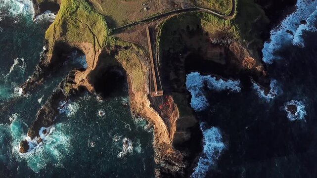 Top down drift over sea caves carved into a basalt headland, Farolim dos Fenais da Ajuda, Sao Miguel, Azores