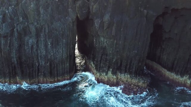 Silent glide through a slot between columnar basalt cliffs with surging Atlantic surf, Sao Miguel, Azores