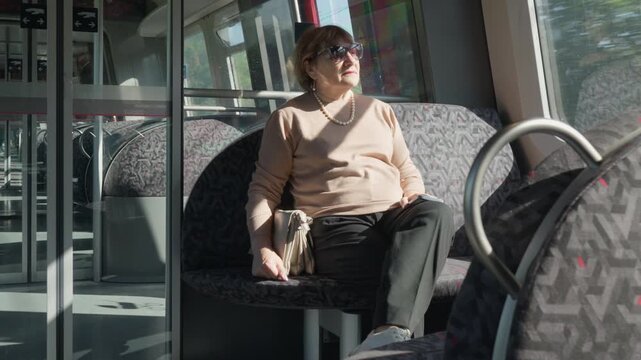A senior passenger sits inside a modern train carriage during a smooth urban transit ride. The spacious passenger cabin offers clean seats and reliable public transport for daily commuting.