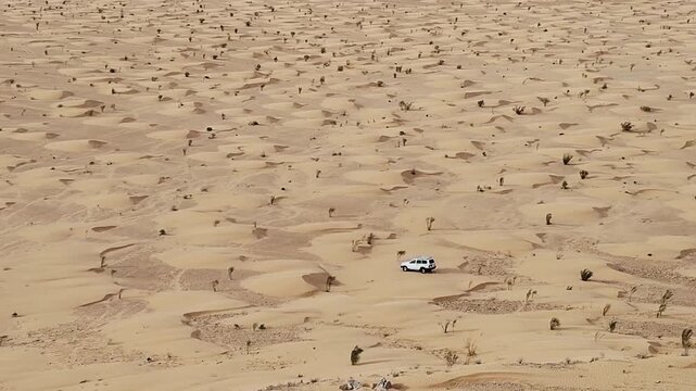 Lone 4x4 crosses a vast empty Sahara  sense of scale shot for travel docs, Grand Erg Oriental, Tunisia