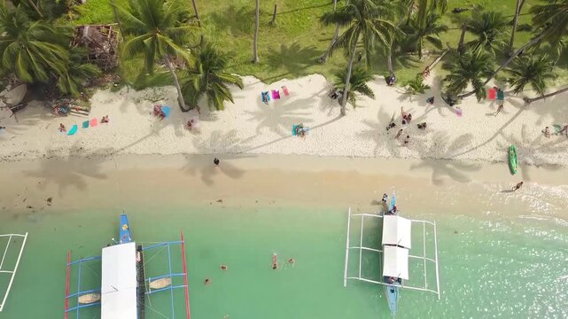 Aerial drone footage of White Beach in Port Barton, San Vicente, Palawan, Philippines. The video shows the long white sand beach, dense coconut palm forest and turquoise tropical waters 