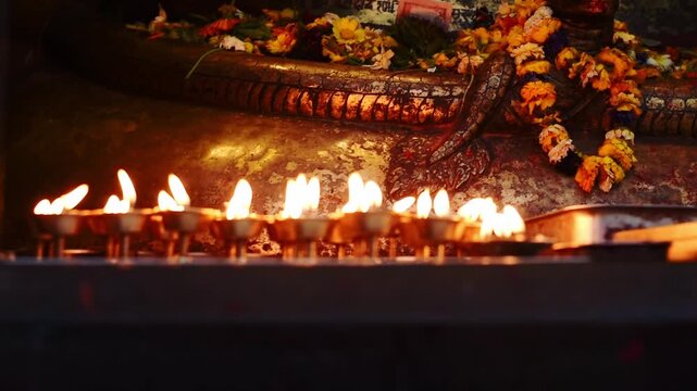 Devotee's hand places a butter lamp at the Shree Kal Bhairav shrine, oil lamps and marigolds, Kathmandu Durbar Square, Nepal