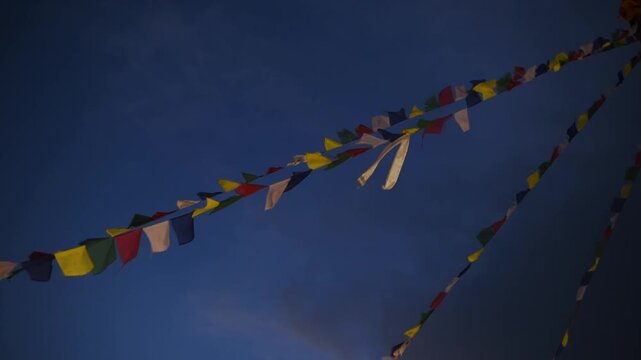 Strings of colourful Tibetan Buddhist prayer flags flutter against a deep blue dusk sky, Kathmandu, Nepal