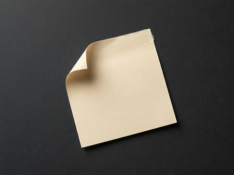 Beige sticky note with a curled corner on black surface