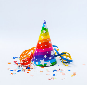 Rainbow-Striped Party Hat with Stars and Confetti on White Background