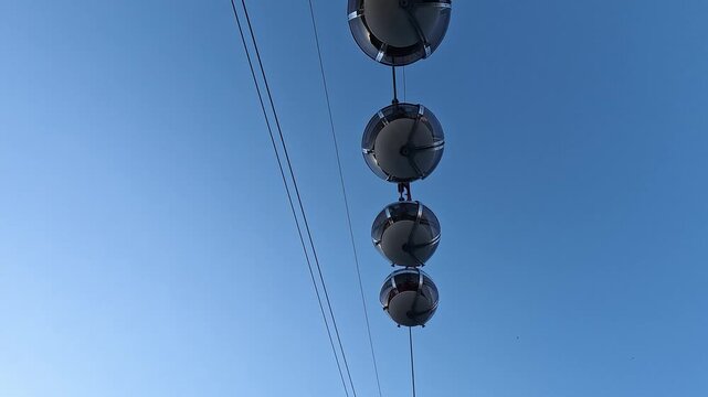 Spherical Les Bulles cable car cabins climbing to the Bastille against blue sky, Grenoble, Auvergne-Rhone-Alpes, France