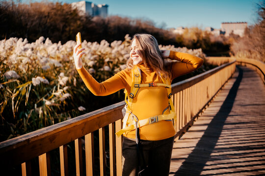 Playful woman on autumn hike taking selfie photo with mobile phone - content creation. Cheerful female traveler posing for social network outdoor. Digital lifestyle and vanity concept.