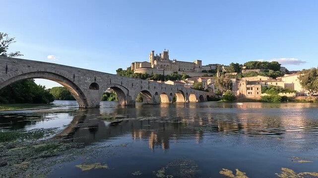 Old town and Cathedrale Saint-Nazaire reflected in the Orb beside the arched Pont Vieux, Beziers, Herault, France