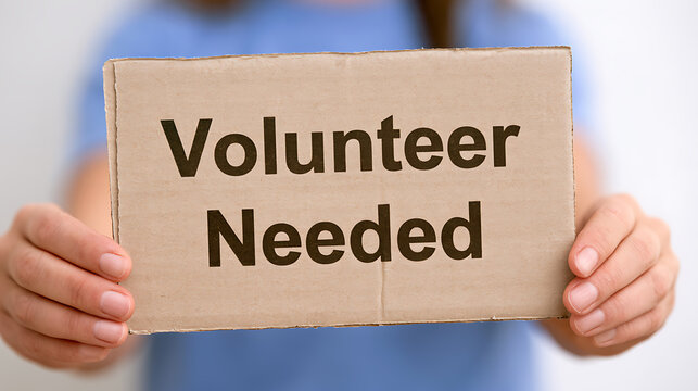 A person hold a cardboard sign with volunteer needed text message for social service charity community project and humanitarian campaign work
