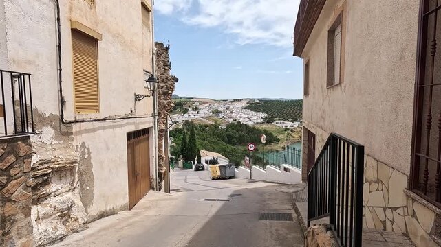 Steep whitewashed street descending toward the Embalse de Iznajar reservoir and olive hills, Iznajar, Cordoba, Andalucia, Spain