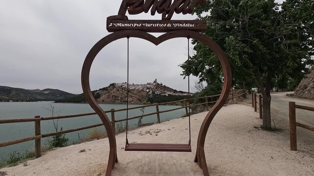 Heart-shaped swing frame by the Embalse de Iznajar framing the hilltop town and castle, Iznajar, Cordoba, Andalucia, Spain