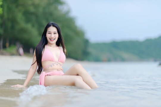 Joyful Woman in Pink Swimsuit Relaxing at Beach on Summer Day